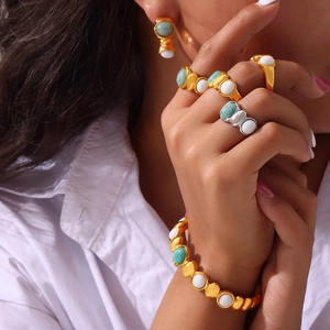 Golden titanium steel jewelry set with green and white inlaid stones worn by a model