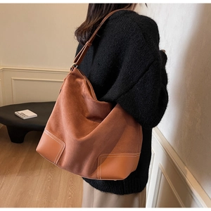 Detail of vintage brown suede tote bag showing leather stitching and wide shoulder strap