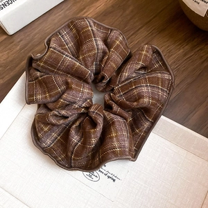 Détail d'un chouchou à carreaux marron café avec de fins fils métalliques dorés