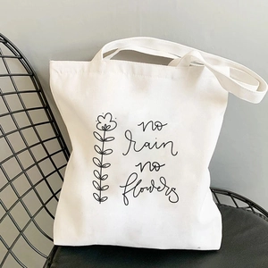 Detail of white canvas tote bag with butterfly floral print and no rain no flowers text