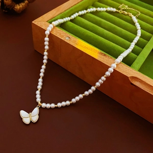 Détail d'un collier de perles avec pendentif papillon en nacre sur un écrin en velours