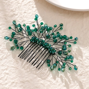Handmade bridal hair comb with green crystals and alloy leaves on textured background