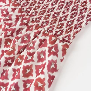 Détail du motif floral rouge sur tissu blanc avec technique de smocks élastiques