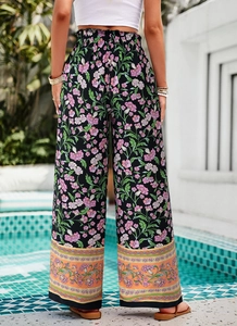Détail du pantalon large taille haute à imprimé floral et bordure bohème au tombé fluide