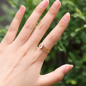 Close-up of golden multi-layer beaded ring with marquise cut zircon on female hand
