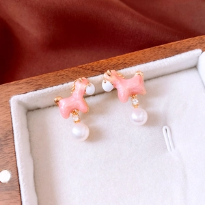 Detailed close-up of 18K gold plated horse earring with pink enamel and pearl drop