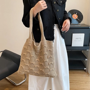 Detail of beige knit tote bag showing textured relief weaving and wide shoulder straps