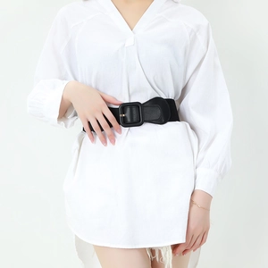 Elegant wide elastic waist belt with large square buckle on a white shirt dress