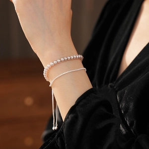 Gros plan d'un bracelet double épaisseur avec perles et zircons au poignet féminin