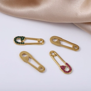Gold pin pendants with green and pink crystals on silk fabric detail view