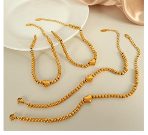 Détail de quatre bracelets à billes plaqués or 18k avec un pendentif en forme de cœur