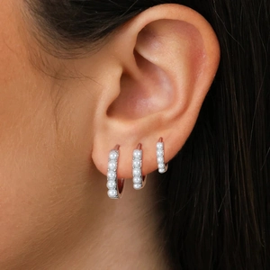 Close-up of model wearing three graduated 18K silver plated pearl hoop earrings