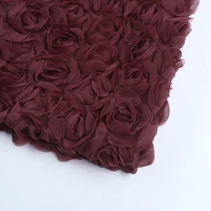 Gros plan de roses en tissu 3D bordeaux et textures de tulle sur une robe élégante