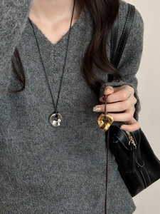 Detail of irregular hollow pendants with gold and silver metallic lava texture on sweater