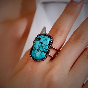 Close-up of adjustable bronze ring with large turquoise stone on a model's hand