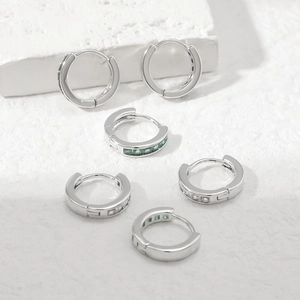 Close-up of S925 silver huggie earrings with white zircon and emerald green gemstones