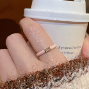 Macro detail of a pale pink enamel ring featuring a rectangular zircon stone and gold trim