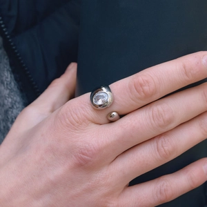 Close-up of polished stainless steel open ring with embedded oval zircon on hand