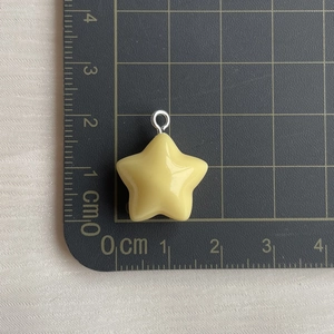 Detailed size measurement of yellow resin star pendant showing 2cm dimensions on grid mat