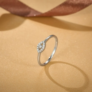 Macro detail of silver Evil Eye ring with white zircons on a yellow textured background