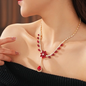 Detail of flower and teardrop pendant necklace with red crystals and gold chain