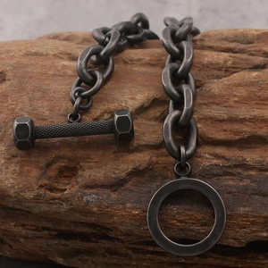 Retro black stainless steel chain bracelet with barbell charm on dark wood background