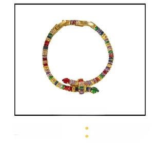 Detailed macro view of snake-shaped bracelet with multicolored zircons and gold plating