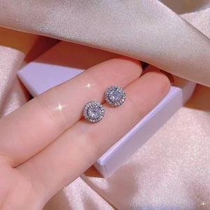 Minimalist silver stud earrings with a large white center stone and sparkling halo detail