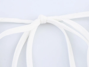 Detail of the white crocheted tie closure on a holiday style backless dress