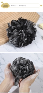 Detail of high-density black and white charcoal bath sponge showing rich foamy lather
