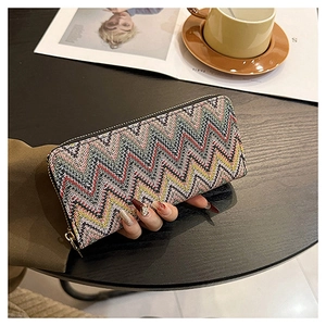 Lifestyle shot of a woven long wallet for women with zigzag pattern on a coffee table