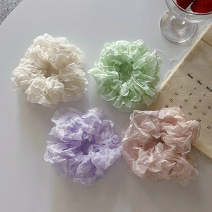Flat lay of four colorful lace mesh scrunchies in pastel tones on white background