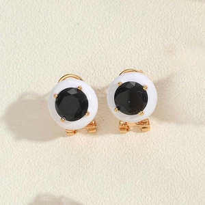 Macro detail of round black rhinestone earrings with white porcelain shell and gold metal