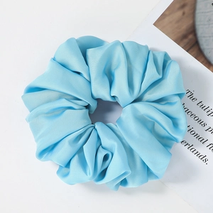 Detailed view of light blue oversized satin scrunchie on a magazine background