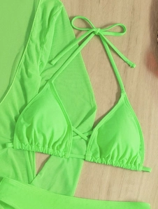 Detailed flat lay of a neon green three-piece bikini set with long sleeve mesh cover-up