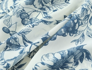 Detailed macro shot of blue floral and cherry print on lightweight breathable white fabric