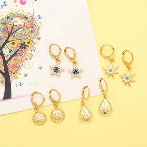 Detail of four pairs of gold celestial earrings with blue gems on a yellow background