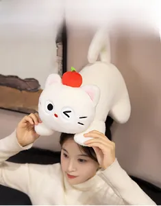 Close-up of white plush cat doll with red apple hat featuring detailed wink embroidery