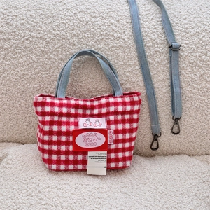 Detail of red plaid wool tote with denim handles, cherry patches and woven label