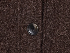 Gros plan sur la texture sergée marron avec polaire et bouton noir à quatre trous
