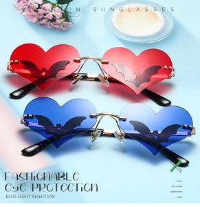 Detail of red and blue heart-shaped bat sunglasses with golden metal frame on blue background