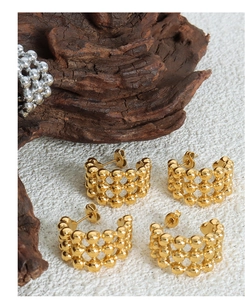 Macro view of textured 18K gold C-shaped earrings with a polished spherical finish