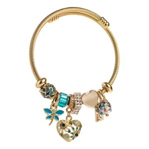 Gold braided cable charm bracelet with dragonfly pendant and heart charms in a white studio setting