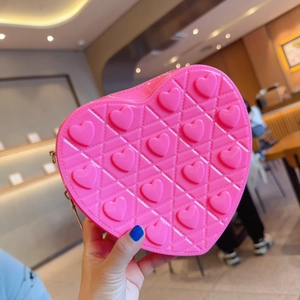 Pink heart-shaped crossbody bag with embossed patterns and gold zipper closure
