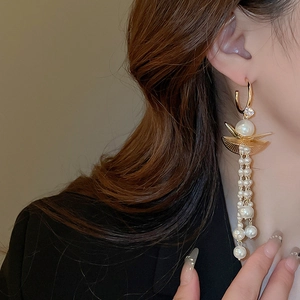 Close-up of golden tassel earrings with pearls and rhinestones on model's ear