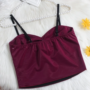 Détail du caraco en satin bordeaux avec bretelles noires sur tapis en peluche blanc