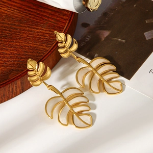 Detail view of gold leaf earrings with white enamel finish on a minimalist background