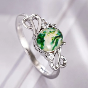 Macro detail of silver ring with oval green moss agate and heart-shaped hollow design