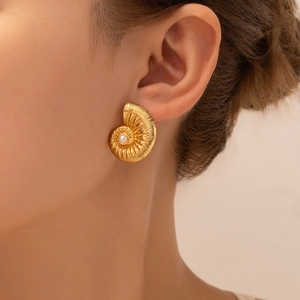 Detail of vintage gold shell earrings with pearl inlay worn on model's ear