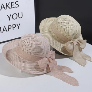 Foldable women's straw sun hat with large bow decoration in pink and beige colors